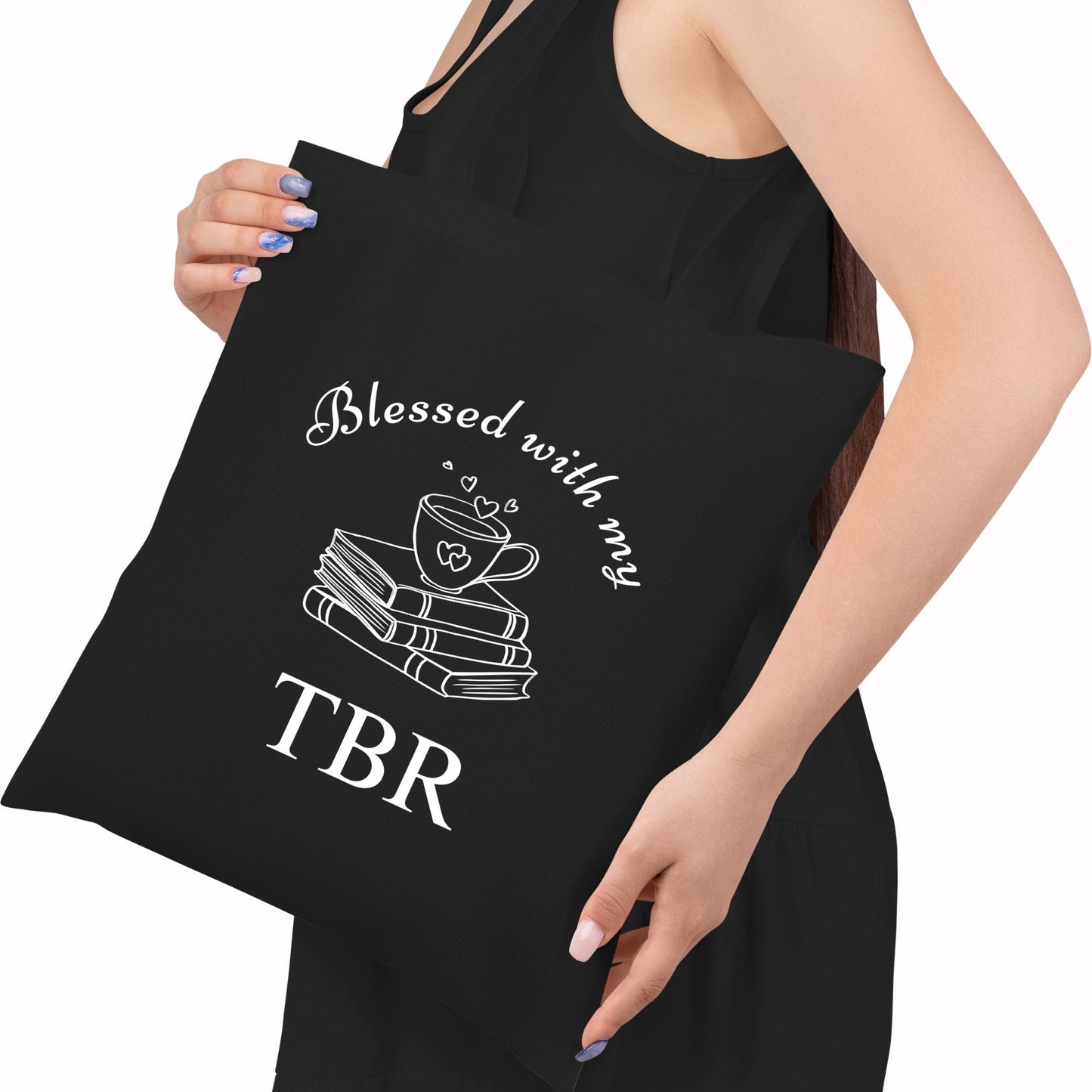 Black book lover tote bag with 'Blessed with my TBR' text and graphic held by a person. Aesthetic library bag, gift for readers.