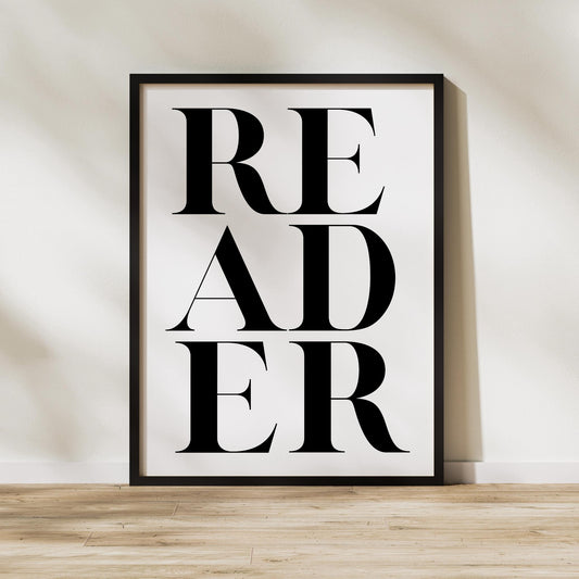 "READER" printable wall art – placed against beige wall - modern typography reading nook decor.