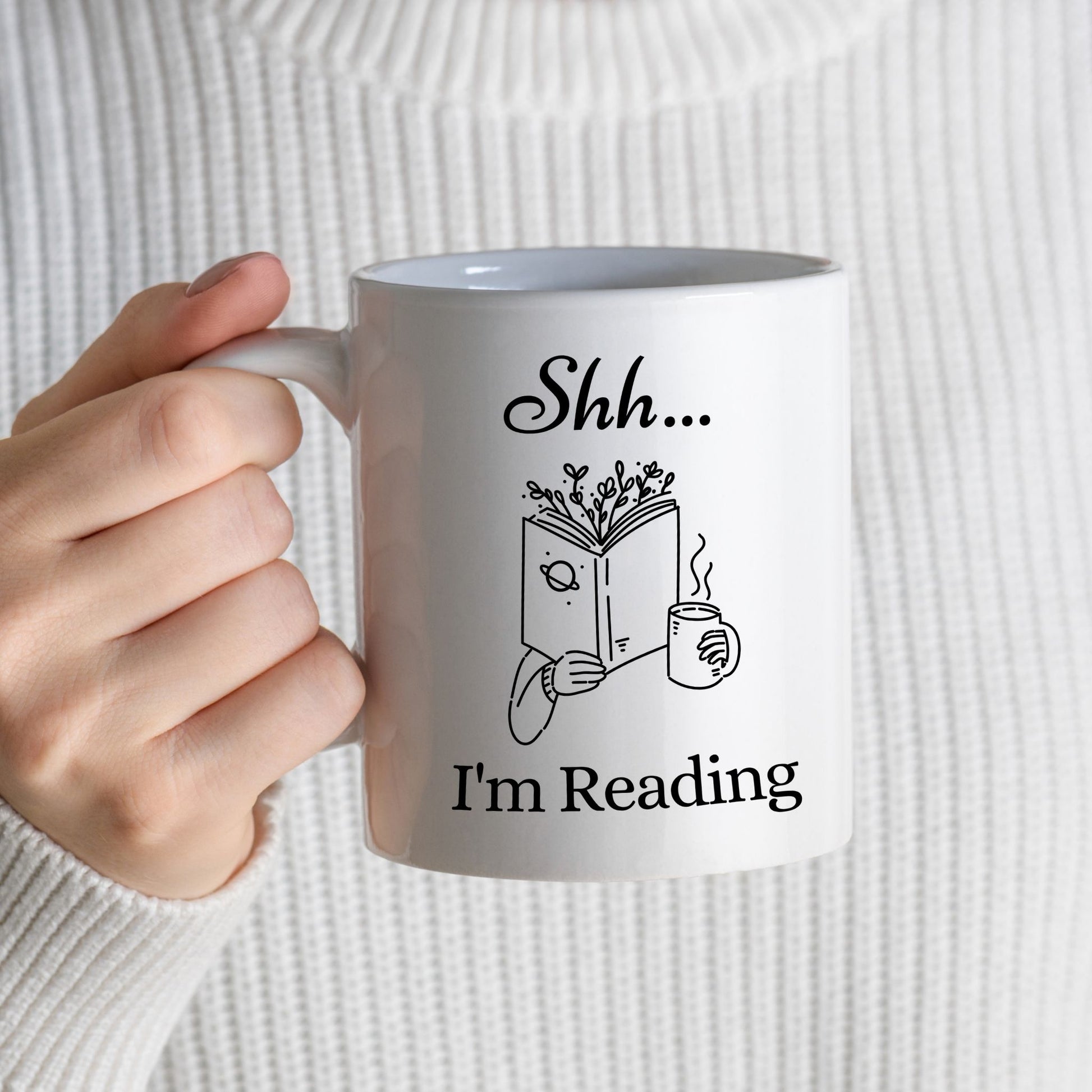 Book lover white ceramic 11oz coffee mug with "Shh... I’m Reading design" held in girl's hand — cute reader gift for tea lovers.